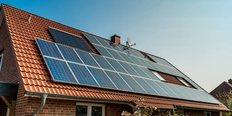 Solar panels fitted across a tiled home roof under a clear sky, a roof mount laid out around the pitch and planes of the existing roof.