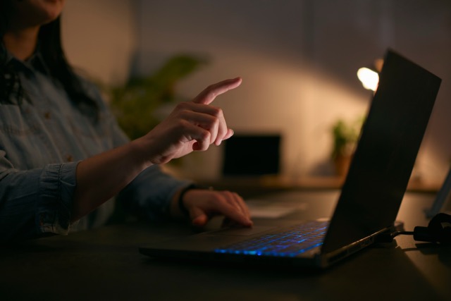 Hands typing on a laptop in a dim room lit by a single lamp, showing how backup power keeps internet and work running through an outage.