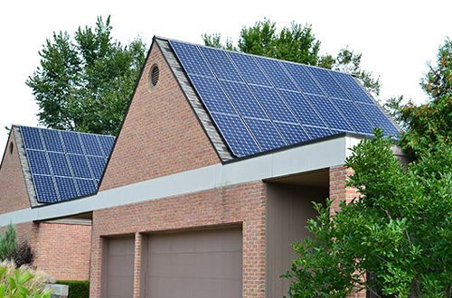 Solar panels mounted on the steep roof of a brick building, a commercial array placed to hold up under snow load and West Michigan weather.
